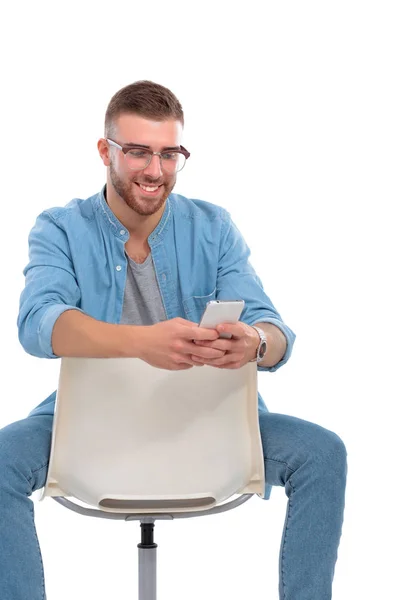 Jeune homme assis sur une chaise et utilisant un téléphone portable — Photo