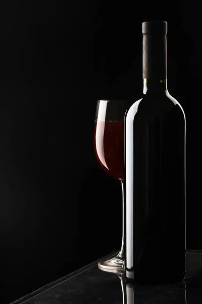 Verre de vin et une bouteille sur fond noir — Photo