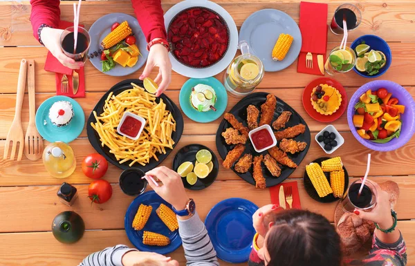 Top view grupo de pessoas jantando juntas enquanto sentadas à mesa de madeira — Fotografia de Stock