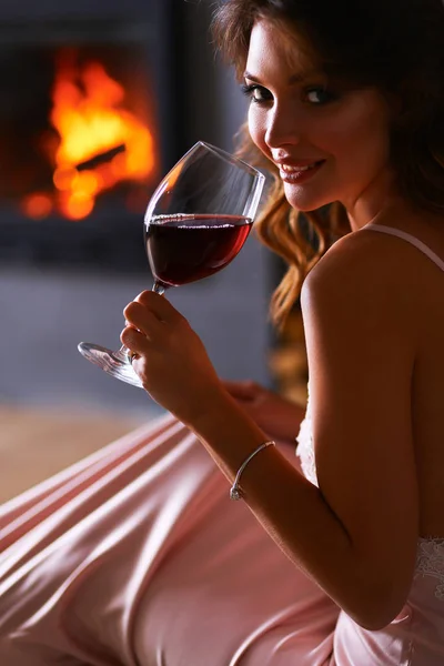 Frau mit einem Glas Wein am Kamin — Stockfoto