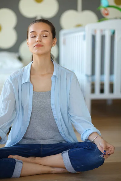 Mujer joven haciendo yoga en casa en la posición de loto — Foto de Stock