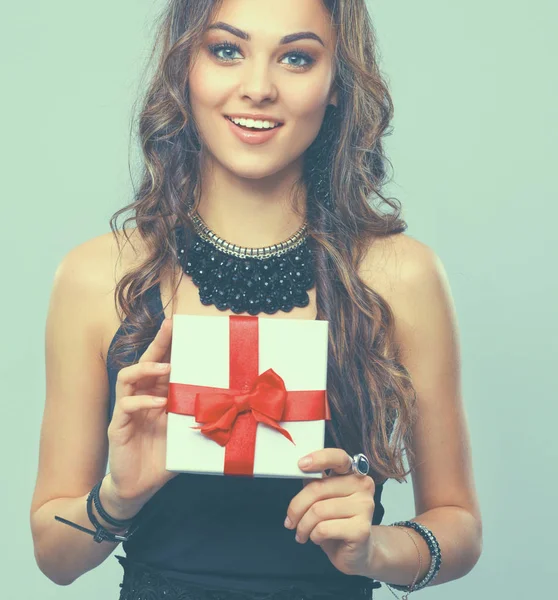 Молода жінка щаслива посмішка тримає подарункову коробку в руках, ізольовано на сірому фоні — стокове фото