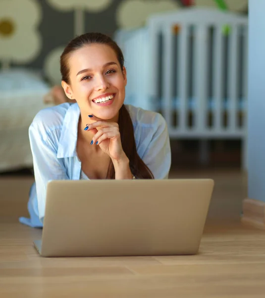 Ung vacker kvinna hemma liggande på golvet med laptop — Stockfoto