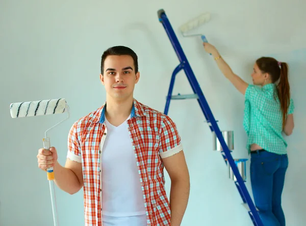 Portrait of happy smiling young couple painting interior wall new house — Stock Photo, Image