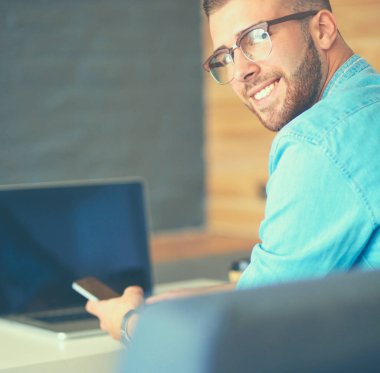 Genç adam kullanarak telefon ve dizüstü bilgisayarda çalışır