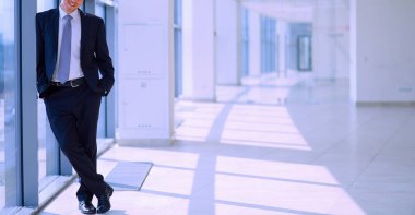 Koridorda pencere yakınındaki şirketi ayakta başarılı iş adamı