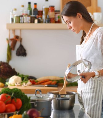 Mutfakta ahşap kaşıkla yemek pişiren kadın