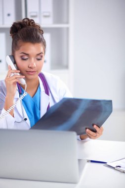 Masada oturan genç bayan doktor röntgen üzerinde çalışıyor.