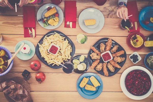 Top view of group of people having dinner together while sitting at wooden table — Stock Photo, Image