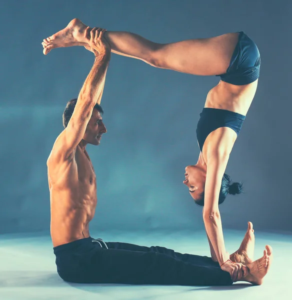 年轻夫妇一起练习杂技瑜伽工作室在垫子上 — 图库照片