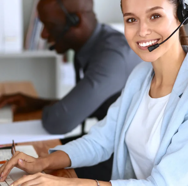 Mensen uit het bedrijfsleven met headsets computers gebruiken in office — Stockfoto