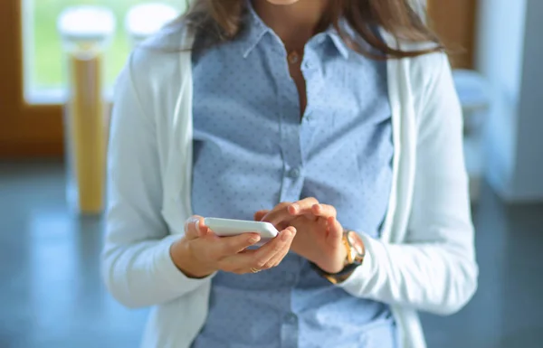 Happy woman drinking tea in the kitchen at home and talking on the phone — Stock Photo, Image