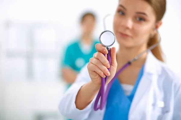 Doctora joven escuchando estetoscopio de pie en el hospital —  Fotos de Stock