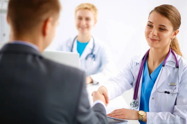 Belle jeune femme médecin souriante assise au bureau — Photo