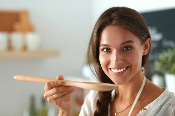 Mujer joven parada junto a la estufa en la cocina —  Fotos de Stock