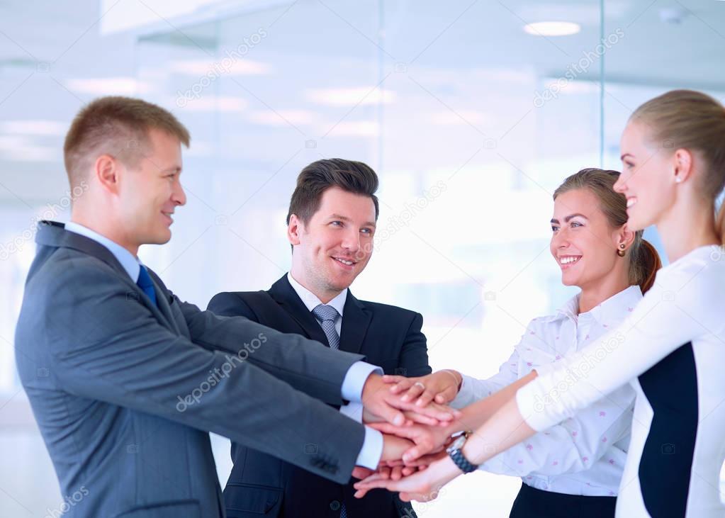 Business team joining hands together standing in office