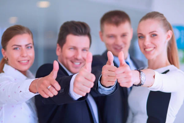 Feliz equipo de negocios mostrando pulgares hacia arriba en la oficina — Foto de Stock