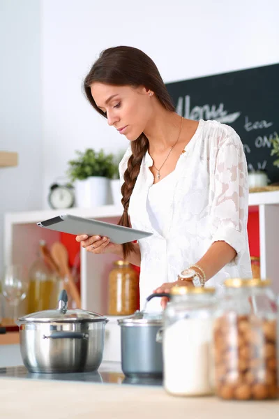 Jeune femme utilisant une tablette informatique pour cuisiner dans sa cuisine — Photo