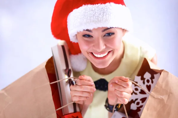 Mujer sonriente en sombrero de santa con muchas cajas de regalo sobre fondo blanco — Foto de Stock