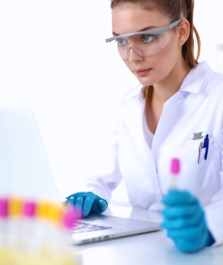 Kadın araştırmacı, beyaz şişeler ve şişelerle çevrili.