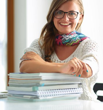 Kitapların arasında masa başında oturan genç bir kadın.