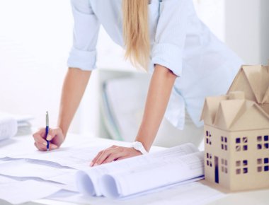 Ofis masasında planları olan, izole edilmiş kadın mimarın portresi.