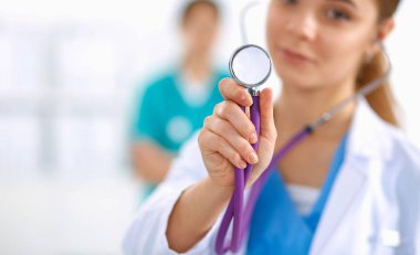 Steteskopu dinleyen genç bayan doktor hastanede duruyor.