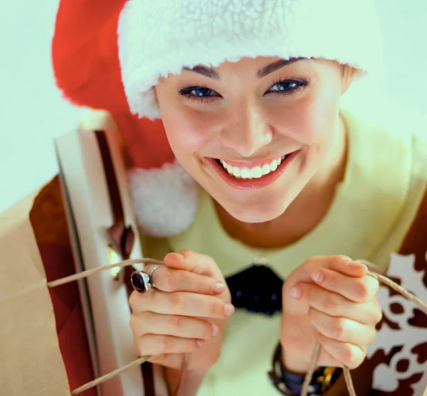 Noel Baba şapkası ile beyaz arka plan üzerinde birçok hediye kutuları gülümseyen kadın — Stok fotoğraf