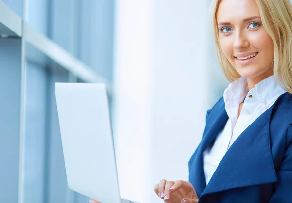 Employée de bureau réussie avec net-book se tient debout dans l'intérieur du gratte-ciel contre une grande fenêtre — Photo