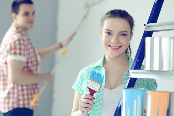 Portrait de heureux sourire jeune couple peinture mur intérieur de la maison neuve — Photo