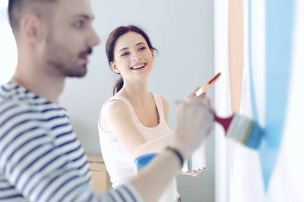 Retrato de feliz joven pareja sonriente pintando la pared interior de la nueva casa —  Fotos de Stock