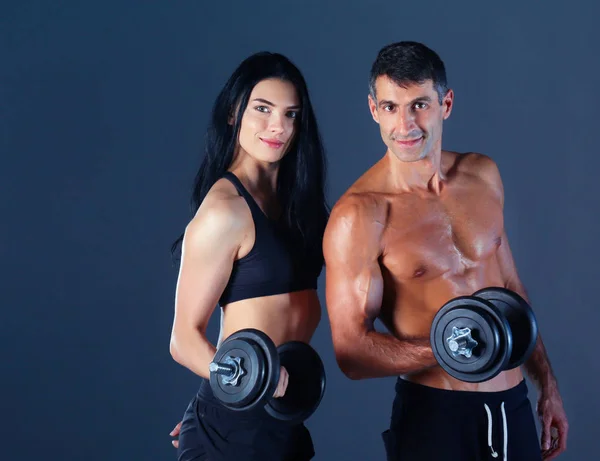 Атлетичные мужчина и женщина с гантелями — стоковое фото