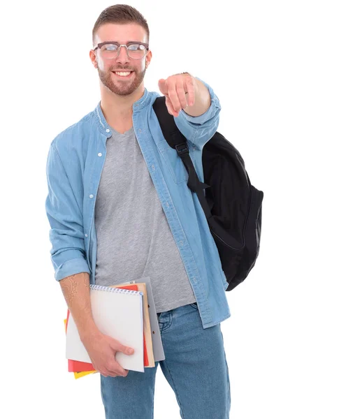 Joven estudiante masculino con una bolsa de la escuela sosteniendo libros y señalándote aislado sobre fondo blanco — Foto de Stock