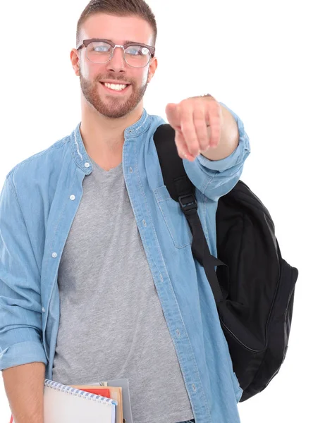 Jovem estudante do sexo masculino com um saco escolar segurando livros e apontando você isolado em fundo branco — Fotografia de Stock