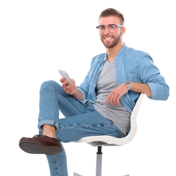 Hombre joven sentado en la silla y el uso de teléfono móvil — Foto de Stock