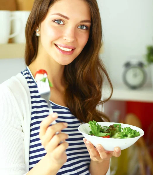 Jovem mulher comendo salada e segurando uma mistura — Fotografia de Stock