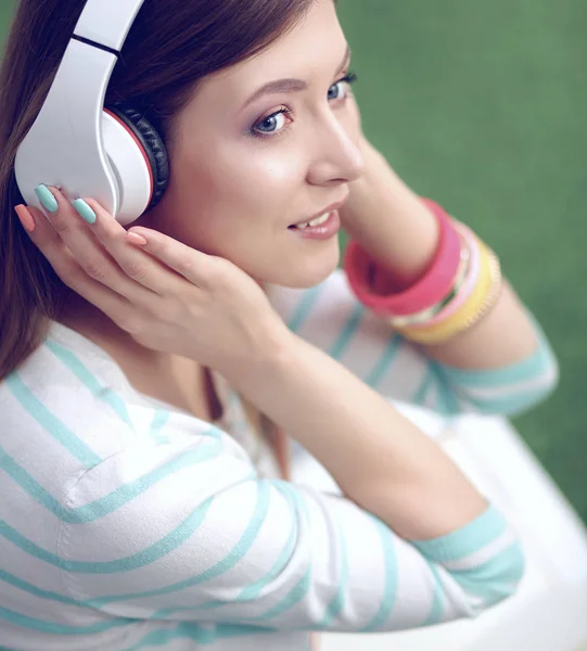 Kvinna som lyssnar på musik sitter på gräset — Stockfoto