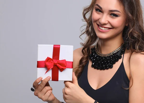 Jonge vrouw gelukkig glimlach houden de doos van de gift in handen, geïsoleerd over grijze achtergrond — Stockfoto