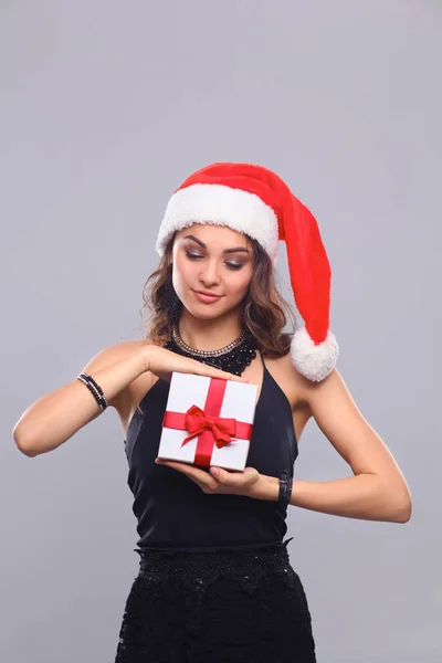 Mladá šťastná žena v santa hat drží vánoční dárek — Stock fotografie