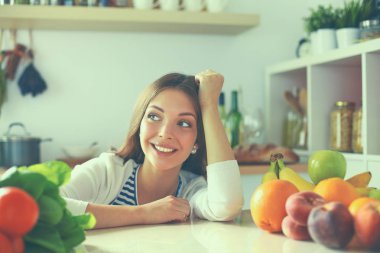 Mutfakta masanın yanında duran genç bir kadın.