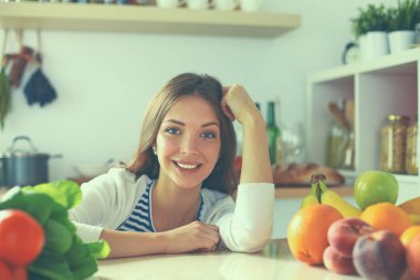 Mutfakta masanın yanında duran genç bir kadın.