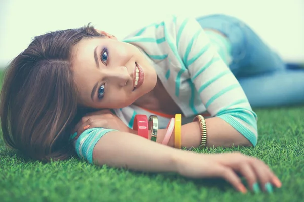 Beautiful young woman lying on the green grass — Stock Photo, Image