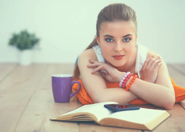 Lachende jonge vrouw liggend op een witte vloer met kussen — Stockfoto