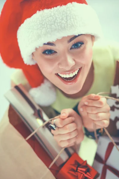 Mujer sonriente en sombrero de santa con muchas cajas de regalo sobre fondo blanco —  Fotos de Stock