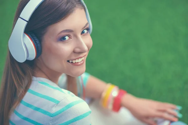 Kvinna som lyssnar på musik sitter på gräset — Stockfoto