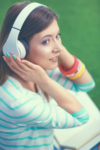 Vrouw luisteren naar de muziek zitten op gras — Stockfoto