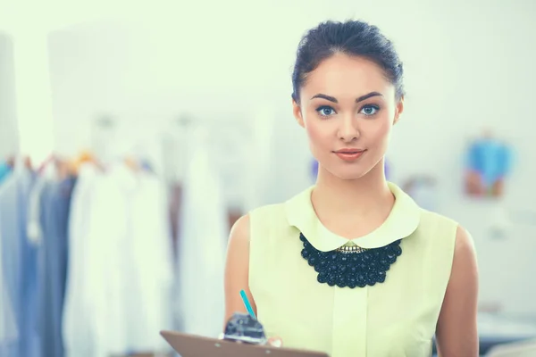 Joven diseñador de moda trabajando en el estudio, de pie con la carpeta — Foto de Stock