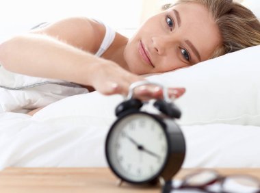 Evdeki yatak odasında uyuyan genç kadın ve çalar saat.