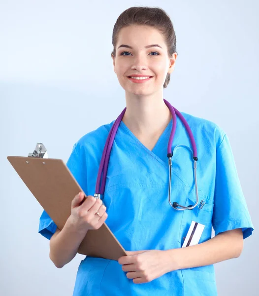 Médico sonriente con una carpeta en uniforme de pie en el hospital — Foto de Stock