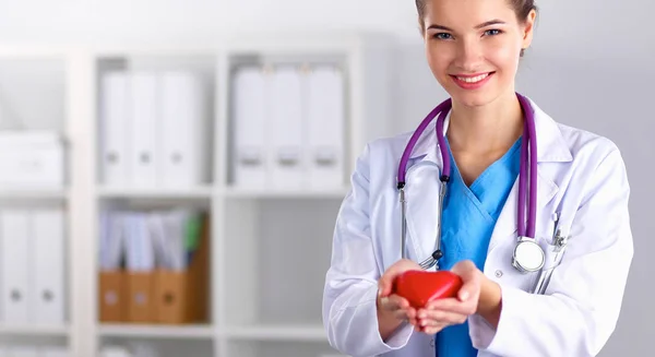 Jovem médico segurando um coração vermelho, de pé — Fotografia de Stock